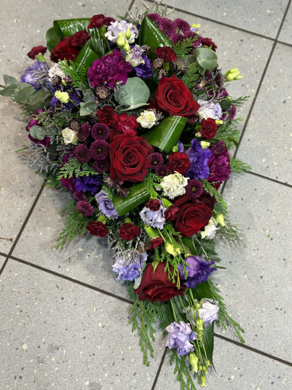 Funeral arrangement: red roses and other dark-shaded flowers