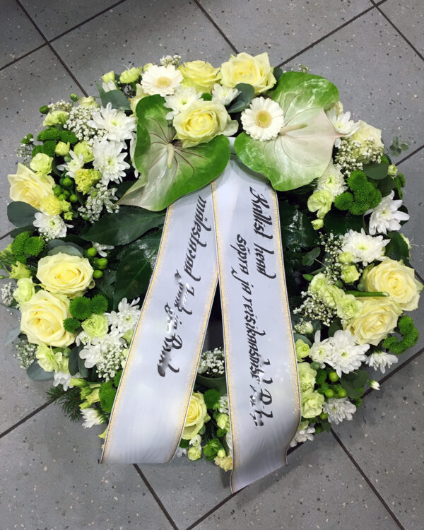 Полный цветов венок из белых, кремовых и зеленых цветов: антуриум, розы, герберы, лисиантус